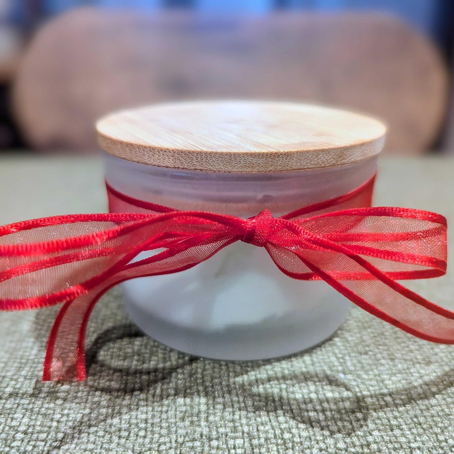 White container with a red ribbon on a textured surface