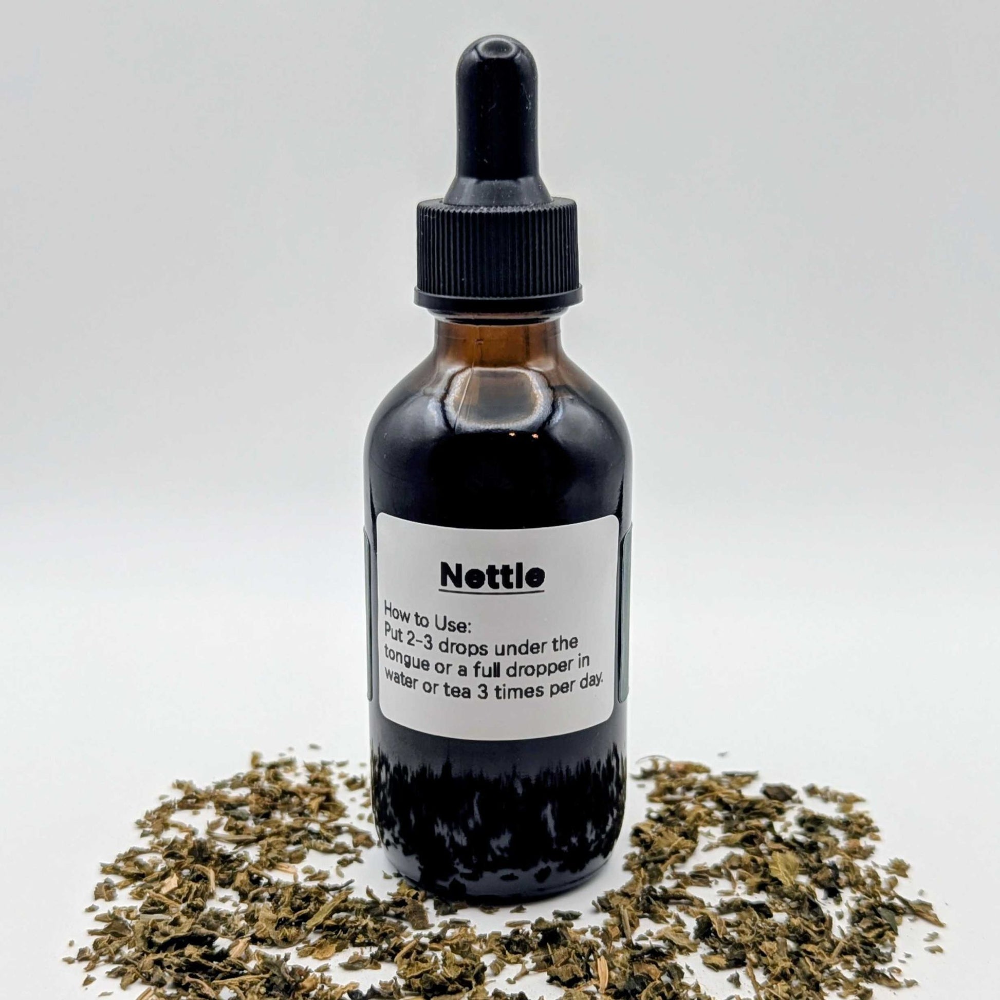 Bottle of Nettle extract with dried nettle leaves on a white background