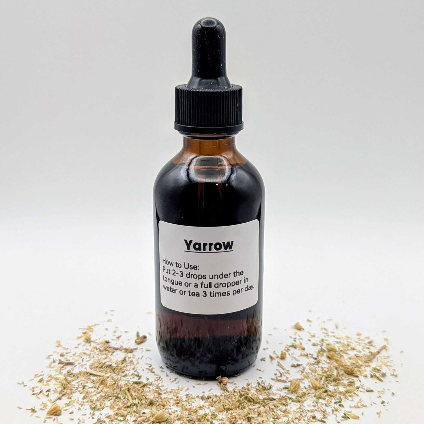 Yarrow tincture bottle with dried yarrow on a white background